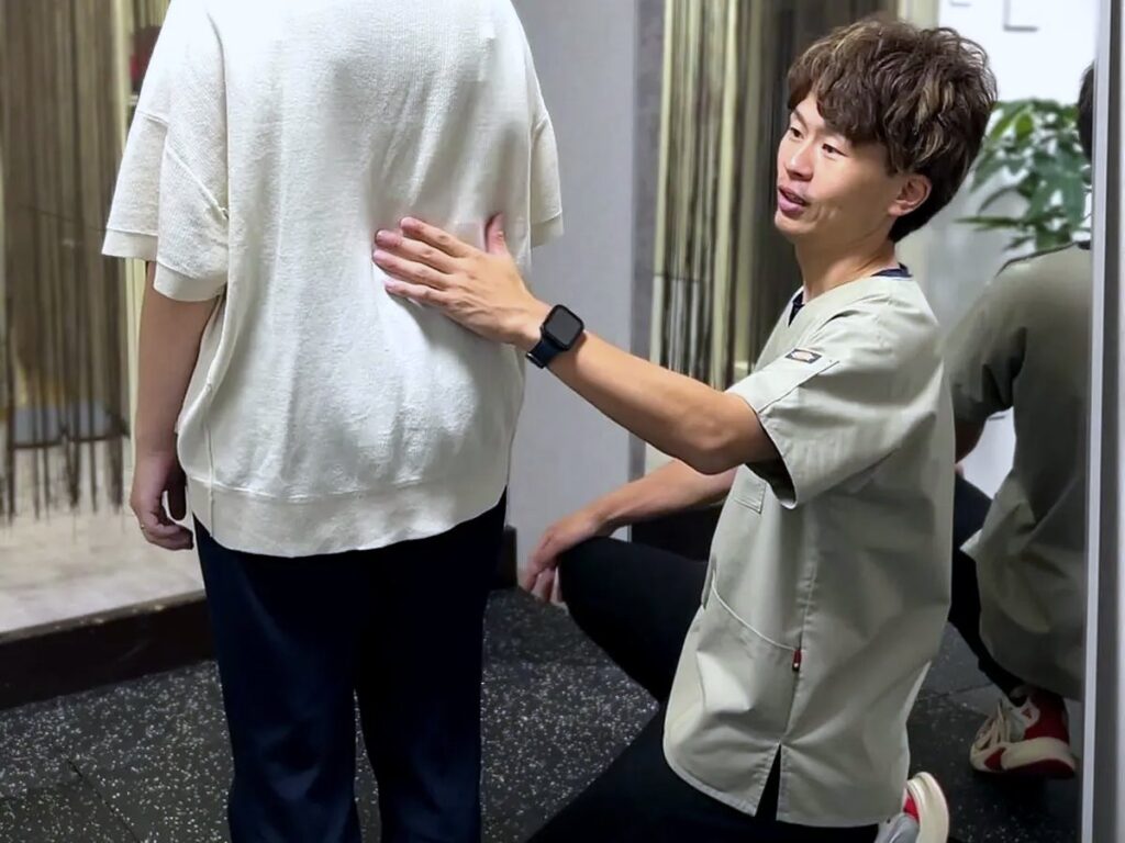 院長が後ろから背中と骨盤の位置を確認している様子